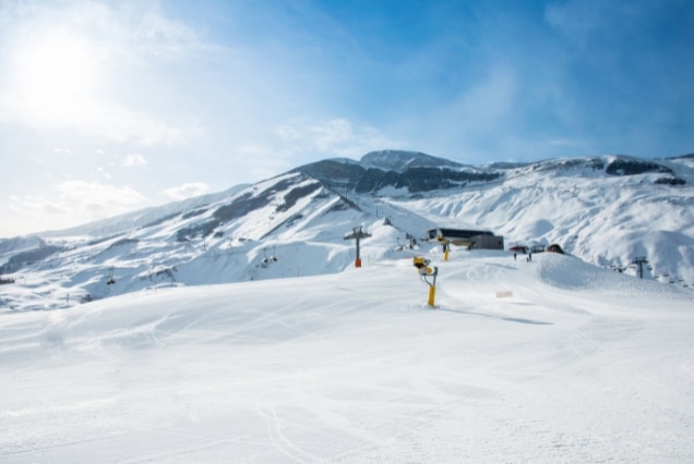 Snow-covered Caucasus Mountains in Azerbaijan at Shahdag Mountain Resort, featuring ski lifts and sunny slopes for a winter holiday package from Dubai.