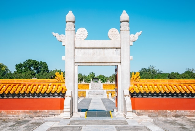 Traditional white stone ceremonial gate and red walls with yellow glazed tiles at Ditan Park, Beijing.