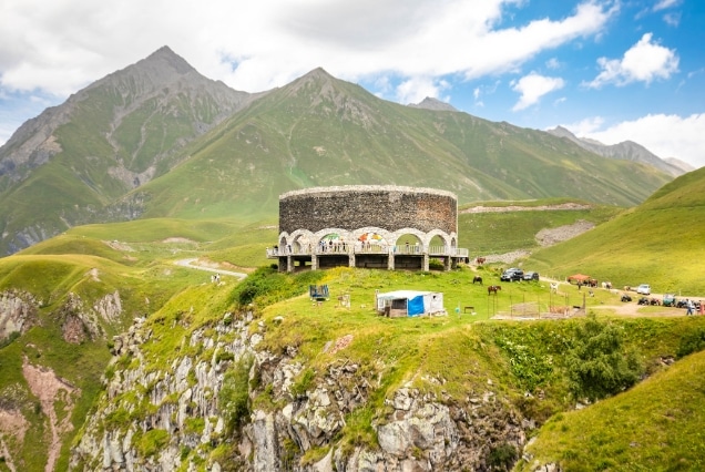 The circular Russia-Georgia Friendship Monument overlooking the lush green Caucasus Mountains in Gudauri, Georgia.