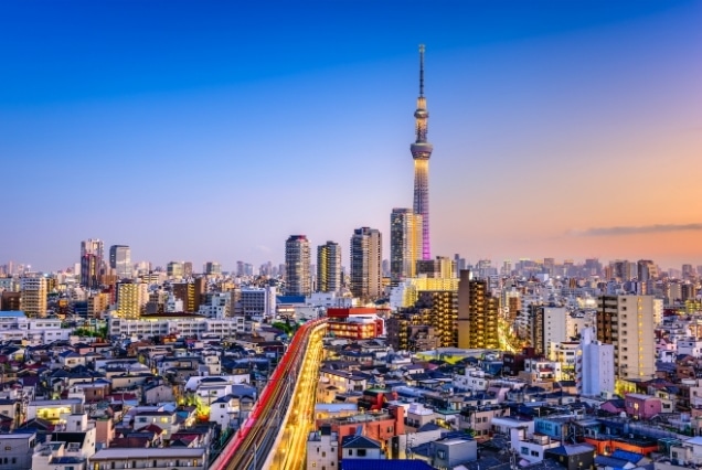 Elevated view of the Tokyo city skyline at sunset featuring the illuminated Tokyo Skytree and urban landscape.