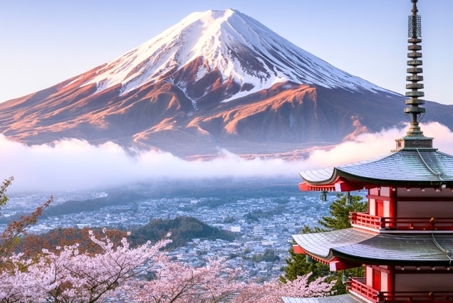 Snow-capped Mount Fuji behind Chureito Pagoda and pink cherry blossoms in Japan.
