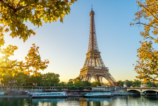Eiffel Tower overlooking the Seine River in Paris during autumn with a river cruise boat.