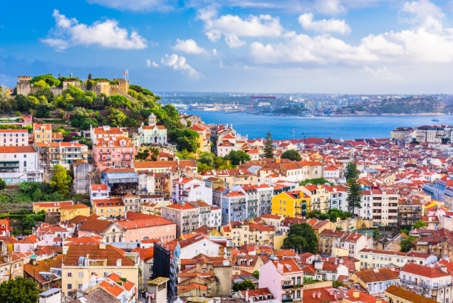 Panoramic view of Lisbon, Portugal, featuring São Jorge Castle on the hill and colorful historic buildings.