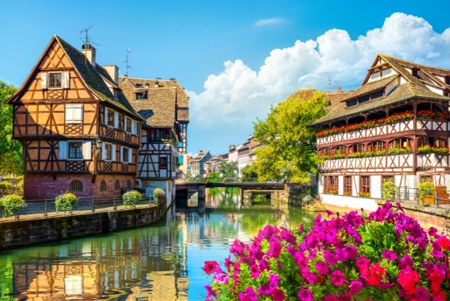 Half-timbered houses and pink flowers along the Ill River canal in La Petite France, Strasbourg, France.