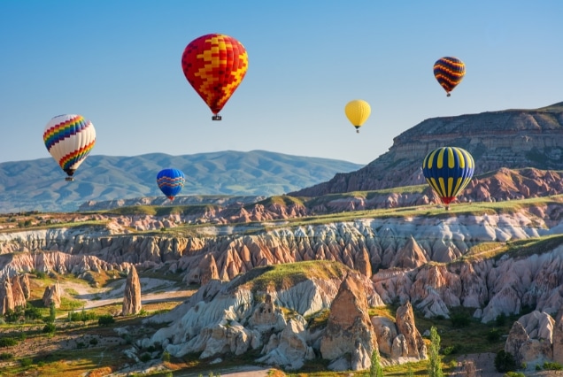 Colorful hot air balloons flying over fairy chimneys in Cappadocia, Turkey; a featured activity for travelers from Dubai.