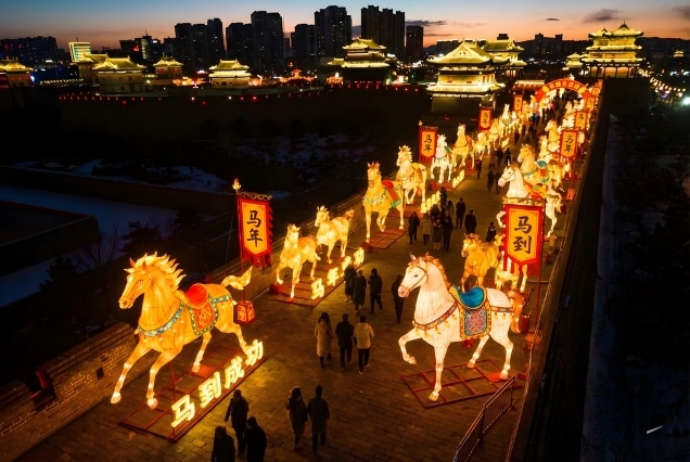 Illuminated horse lanterns on the ancient Xi'an City Wall during the 2026 Year of the Fire Horse festival at sunset.