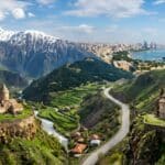 Panoramic view of the Caucasus region showing ancient Armenian monasteries, snowy Georgian mountain peaks, and the modern Baku skyline in Azerbaijan.