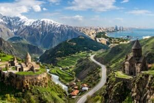 Panoramic view of the Caucasus region showing ancient Armenian monasteries, snowy Georgian mountain peaks, and the modern Baku skyline in Azerbaijan.