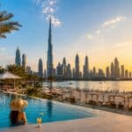 Woman in a resort infinity pool looking at the Burj Khalifa skyline. Is Dubai worth visiting in summer 2026 travel guide.
