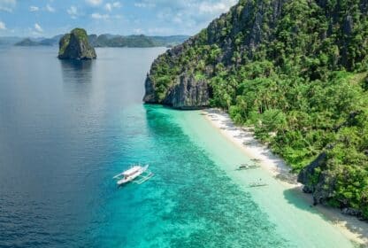 Traditional boat on clear turquoise water at a Palawan beach, highlighting tropical Philippines holiday packages from Dubai.