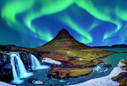 Vibrant green Northern Lights over Kirkjufell mountain and Kirkjufellsfoss waterfall in Iceland, featured in Iceland tour packages from Dubai.