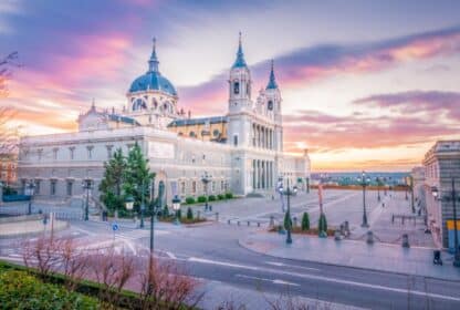 Almudena Cathedral in Madrid, Spain under a vibrant pink sunset sky, showcasing historic European architecture.