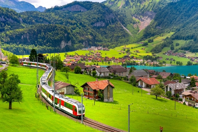 Swiss scenic train passing through a green alpine valley near Interlaken and mountain lakes