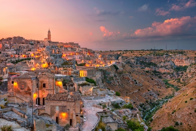 Matera Italy historic Sassi cave dwellings glowing at sunset over the rugged canyon landscape