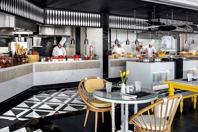 Open kitchen with chefs and dining tables at Fairmont Fujairah Beach Resort restaurant