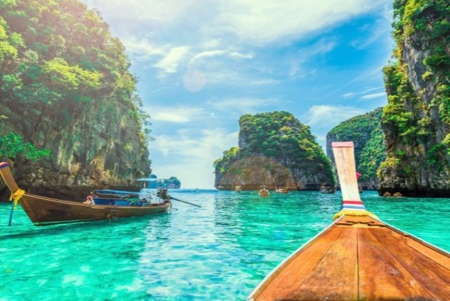 Traditional longtail boats in a turquoise lagoon between limestone cliffs – Phuket and Phi Phi Island Tour Package