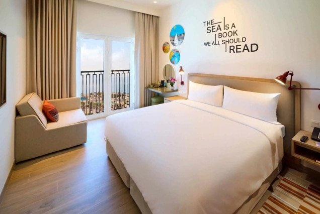 Guest room with a large bed, sofa and balcony at Rove Al Marjan Island Title (34): Guest Room | Rove Al Marjan Island