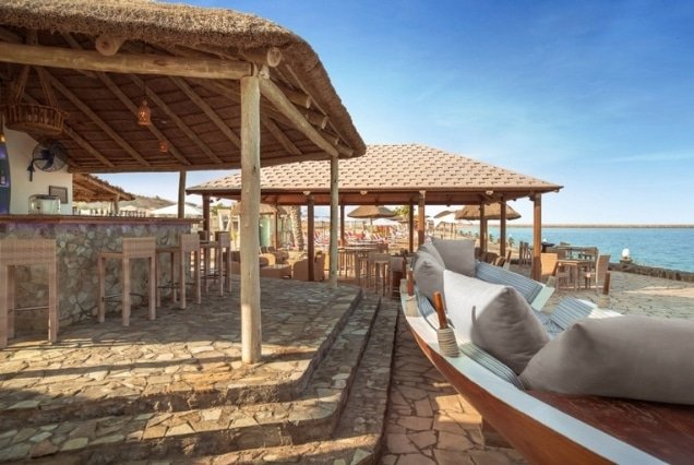 Thatched beach bar and seating by the sea at The Cove Rotana Resort Ras Al Khaimah